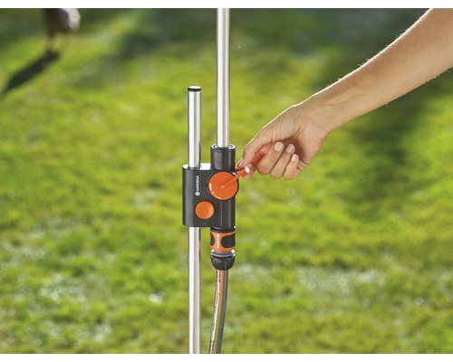 Une main actionne un distributeur d''eau sur un robinet de jardin.