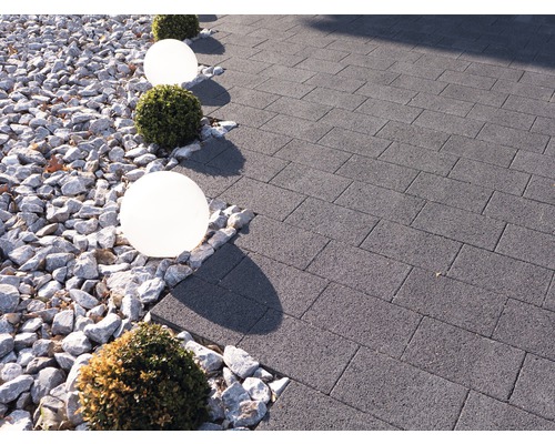 Chemin de jardin pavé de dalles en béton, décoré de gravier, de lampes sphériques et de boules de buis