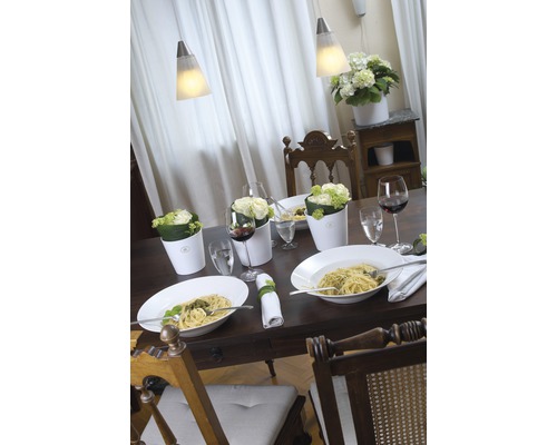Table à manger dressée avec des pâtes, des boissons, des fleurs et des lampes