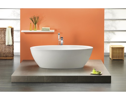 Freistehende Badewanne in einem hellen Badezimmer mit gefliestem Podest und Ablagefläche