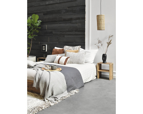 Chambre avec mur en bois, lit, coussins, couvertures, table d''appoint et lampe