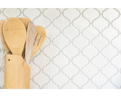 Küchenutensilien aus Holz in Halter vor gemusterter Wand