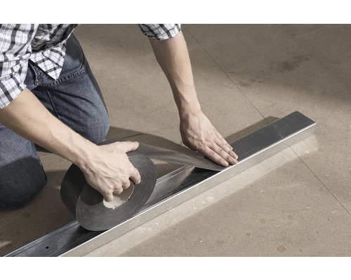 Une personne applique du ruban d''étanchéité sur un profilé métallique.