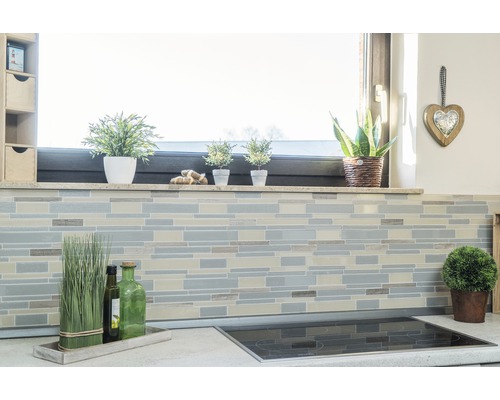 Küchenszene mit Fliesenmosaik an der Wand, Fensterbank mit Dekoration und Kochfeld auf der Arbeitsplatte.