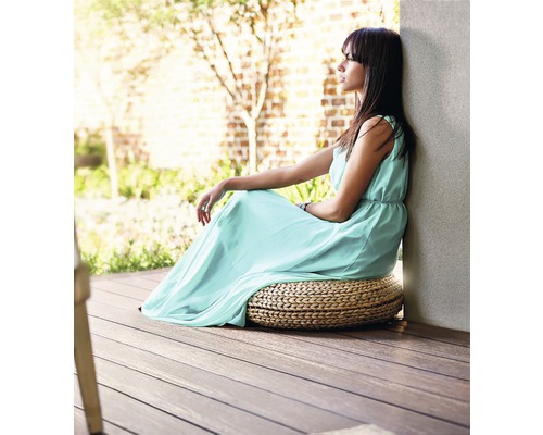Femme assise sur un coussin de siège rond sur une terrasse en bois