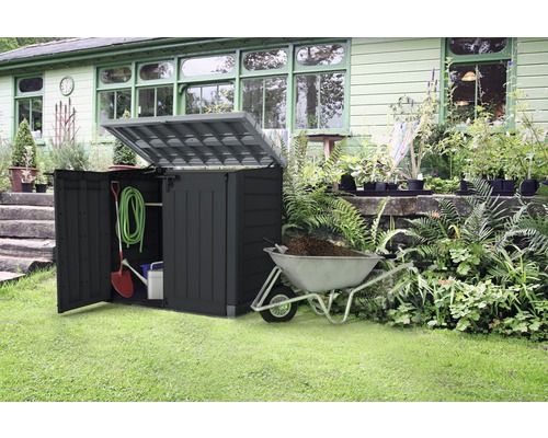 Gartenszene mit einer Gerätebox, geöffnet, mit Gartengeräten und einer Schubkarre gefüllt mit Erde.