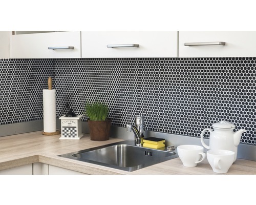 Scène de cuisine avec évier, robinet, carreaux de mosaïque et ustensiles de cuisine sur le plan de travail.