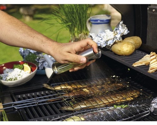 Une personne vaporise de l''huile sur du poisson sur un barbecue.