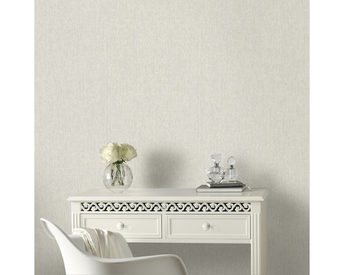 Helle, strukturierte Tapete im Interieur mit Kommode, Blumen und Dekorationsartikeln.