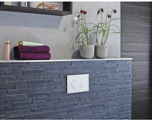 Aménagement de salle de bains avec mur en pierre grise, étagère avec serviettes et plantes