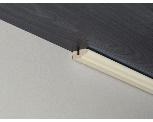 Sockelleiste aus Holz an Wand und Laminatboden