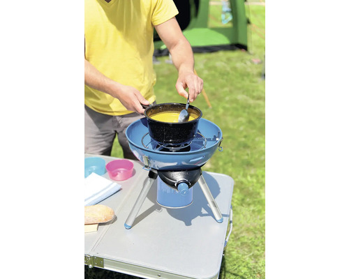 Mann kocht Suppe auf einem Campingkocher im Freien.