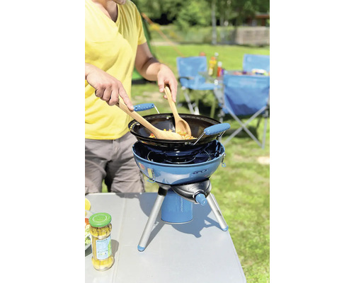 Person kocht im Freien mit einem tragbaren Gaskocher und Wok