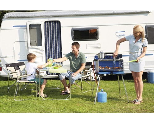 Scène familiale avec caravane, barbecue et mobilier de camping sur une pelouse