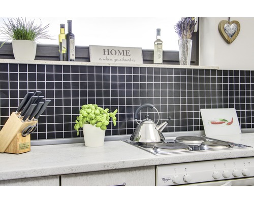 Scène de cuisine avec crédence en carrelage, plaque de cuisson, bouilloire et divers ustensiles de cuisine