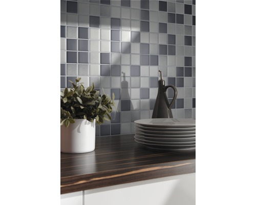 Mur de carreaux de mosaïque au-dessus d''un plan de travail foncé avec vaisselle et décoration