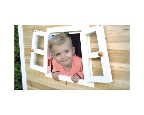 Petit garçon regardant par la fenêtre d''une cabane en bois