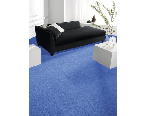 Wohnzimmer mit blauem Teppichboden, schwarzem Sofa und weißen Beistelltischen.