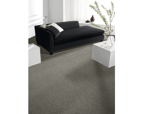 Heller Raum mit grauer Auslegware, schwarzem Sofa und weißen Beistelltischen