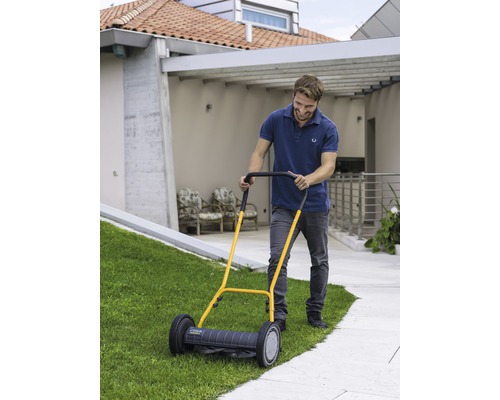 Homme utilisant une tondeuse à gazon manuelle dans le jardin