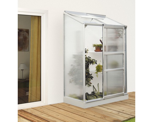 Anlehngewächshaus Vitavia Ida 900 Hohlkammerplatten 4 mm 131x69 cm Aluminium Anlehngewächshaus mit Pflanzen neben einem Fenster auf einer Holzterrasse