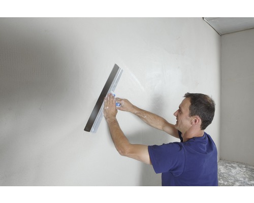 Homme lissant un mur avec une spatule