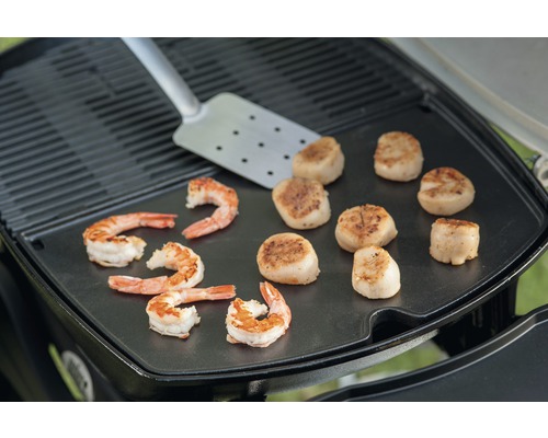 Crevettes et coquilles Saint-Jacques grillées avec spatule sur plaque de cuisson