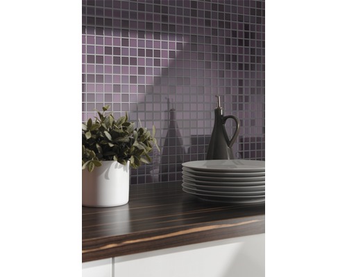 Scène de cuisine avec carreaux de mosaïque, plan de travail, vaisselle, plante et bouteille d''huile