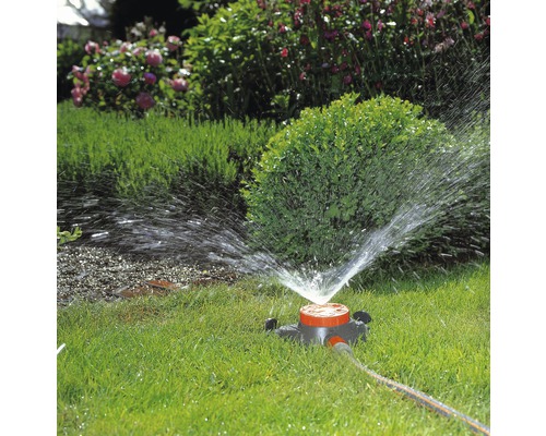 Rasensprenger bewässert Rasenfläche im Garten