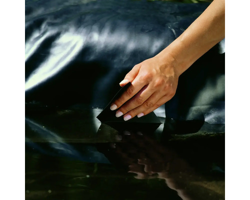 Une personne répare une bâche de bassin avec un kit de réparation.