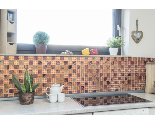 Scène de cuisine avec mur en carreaux de mosaïque, plantes et ustensiles de cuisine sur le plan de travail.