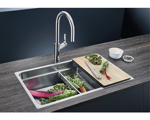 Spüle mit Armatur, Schneidebrett, Gemüseschale und geschnittenem Gemüse.