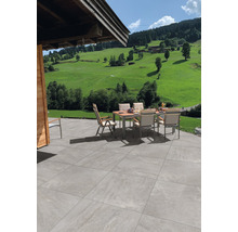 Terrasse mit Gartentisch und Stühlen vor einer grünen Landschaft.