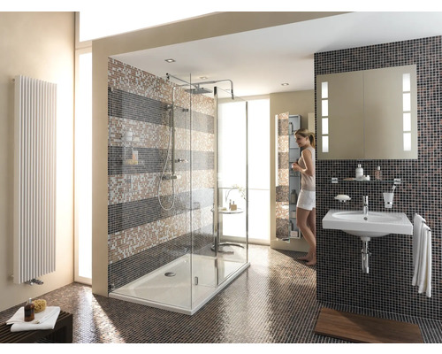 Salle de bains lumineuse avec douche, lavabo et radiateur devant des carreaux de mosaïque