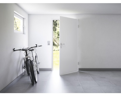 Pièce lumineuse avec porte ouverte, vélos au mur et fenêtre