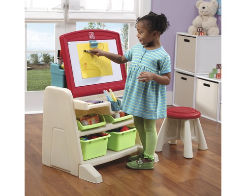 Enfant peint sur un chevalet avec des paniers de rangement et un tabouret