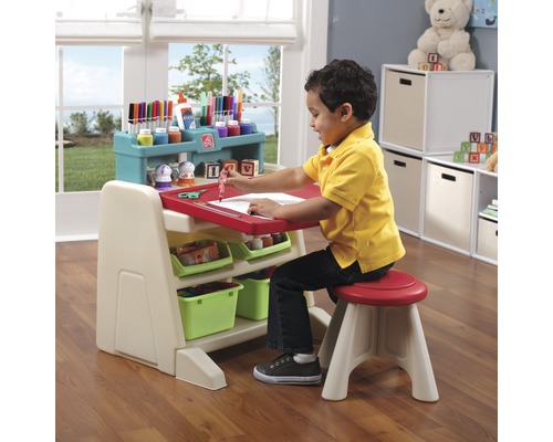 Enfant assis à un bureau d''enfant avec une chaise dessinant sur du papier