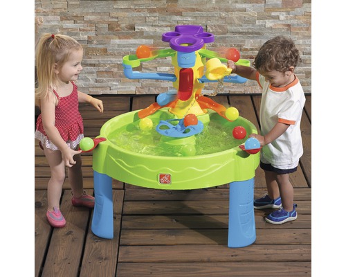 Kinder spielen mit einem interaktiven Wasserspieltisch im Freien.