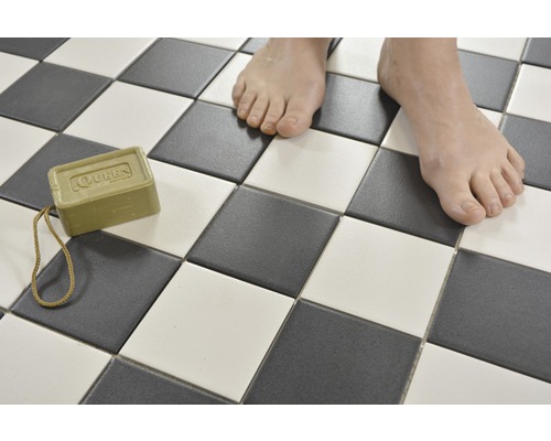 Quadratische Fliesen in Schachbrettmuster mit Stück Seife und Füssen