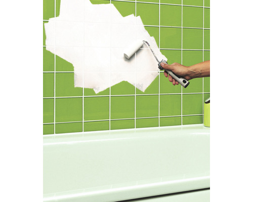 Une personne peint des carreaux dans la salle de bain avec un rouleau à peinture.