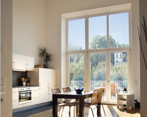 Espace de vie lumineux avec kitchenette, table à manger et grande fenêtre donnant sur la verdure