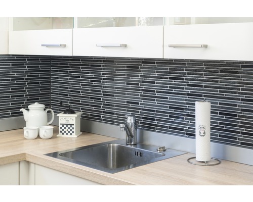 Scène de cuisine avec évier, robinet, plan de travail, vaisselle et ustensiles de cuisine devant un mur en mosaïque noire