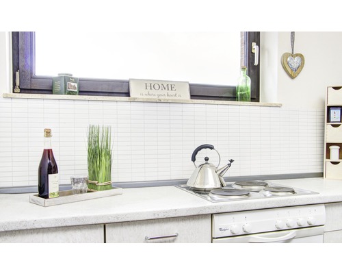 Scène de cuisine avec plaque de cuisson, bouilloire, bouteille, verre et éléments décoratifs.