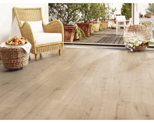 Heller Raum mit Laminatboden, Korbstuhl und Obstschale