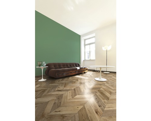 Salon avec canapé marron, parquet en chevrons et mur vert