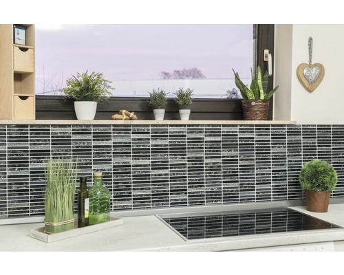 Scène de cuisine avec des carreaux de mosaïque sur le mur, des plantes et des ustensiles de cuisine sur le plan de travail.