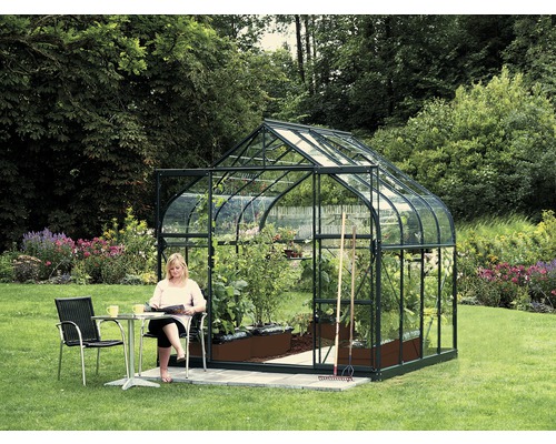 Gewächshaus Vitavia Diana 6700 Einscheibensicherheitsglas 3 mm 264x258 cm grün Gewächshaus im Garten mit Pflanzen und Frau an einem Tisch