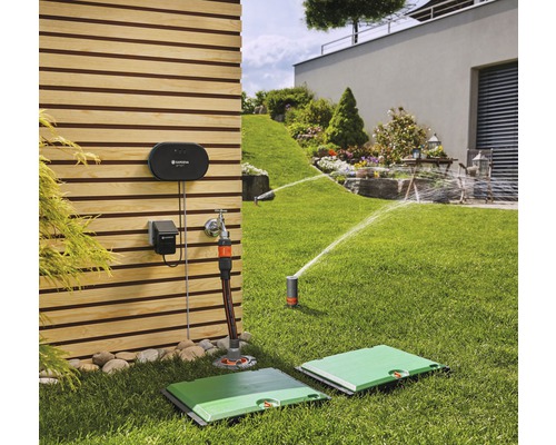 Szene mit einem Garten mit einem Bewässerungssystem, inklusive Versenkregnern und Steuerungsgeräten an einer Holzwand.