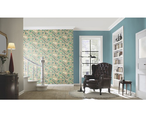 Wohnzimmer mit floral gemusterter Tapete, Sessel und Bücherregal