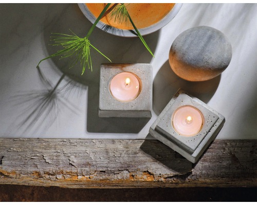 Szene mit zwei Teelichthaltern aus Beton, einer Steinkugel und einer Pflanze in einer Schale
